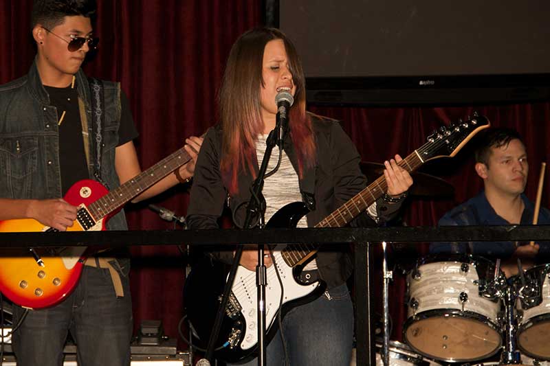 Teen playing guitar on stage after guitar lessons program ended